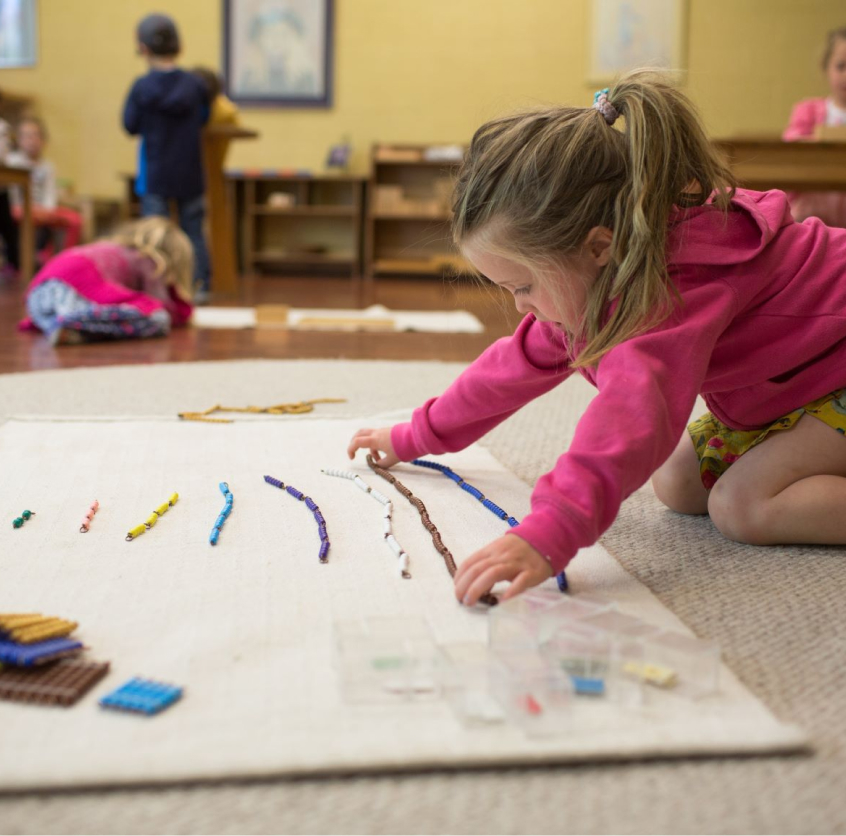 girl student playing with art beeds on ground