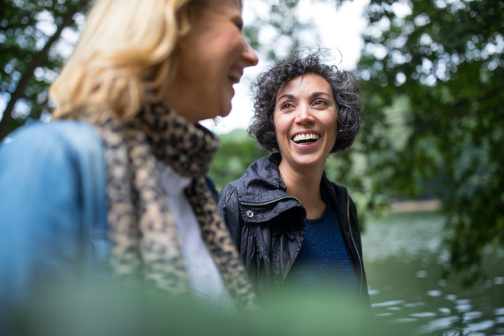 Women walking through forest near body of water