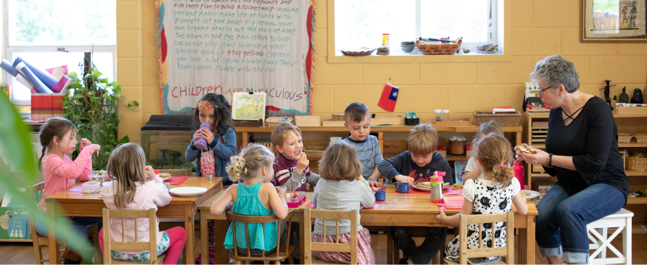 students sitting at long desk with teacher